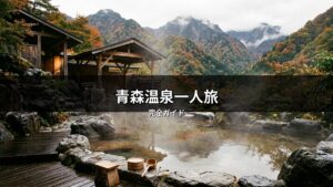 青森の紅葉と山々が美しい露天風呂の風景。湯気立つ温泉と和風建築が魅力で、一人旅に最適な癒しの空間を表現しています。青森温泉一人旅の完全ガイドにふさわしい一枚。