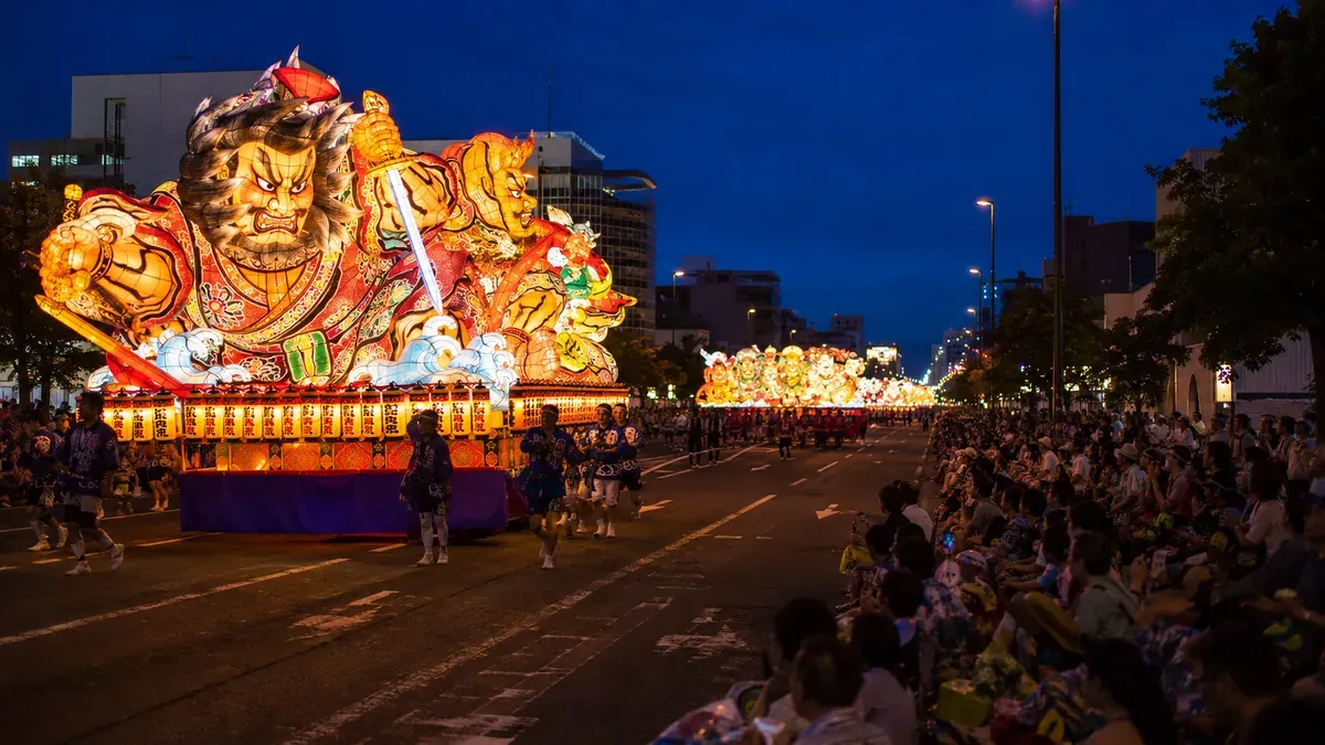 青森ねぶた祭の多様なねぶたが夜の運行コースを進む活気ある情景