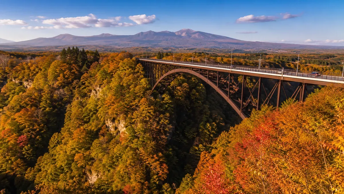 青森県城ヶ倉大橋から望む、紅葉に彩られた城ヶ倉渓流と八甲田連峰