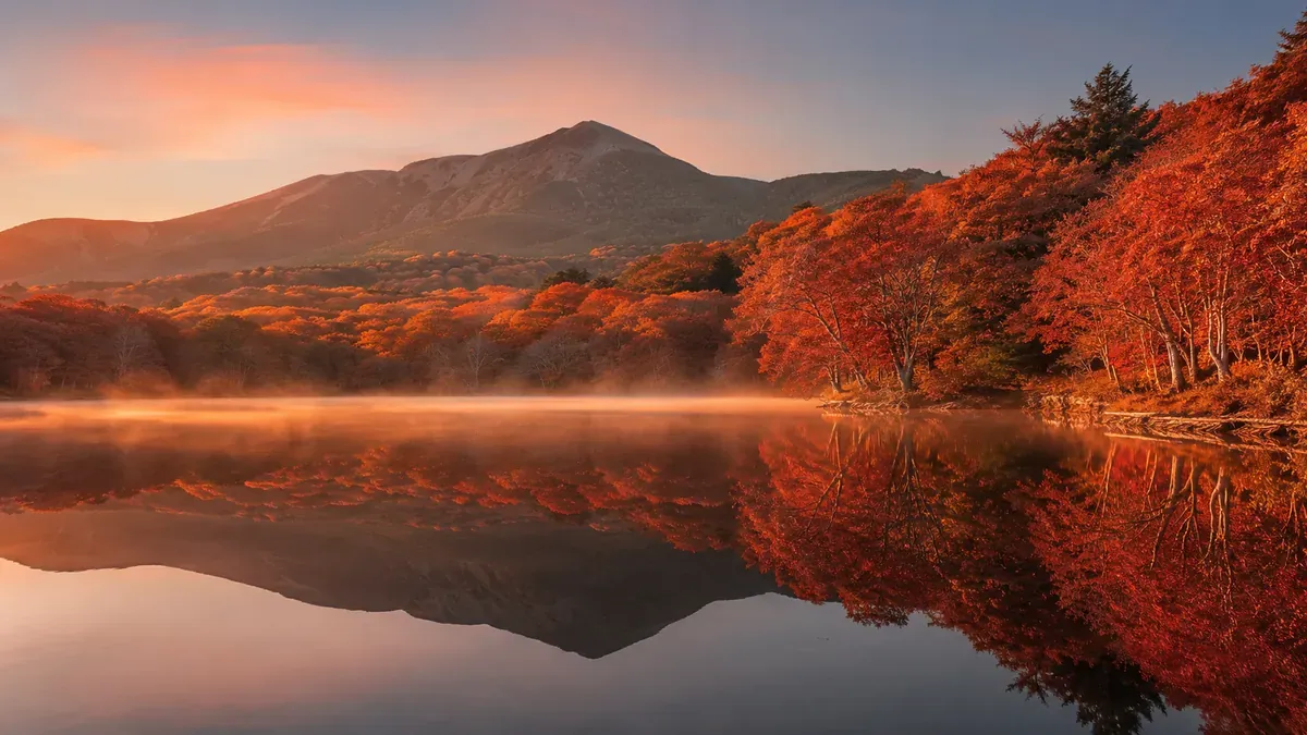 青森県八甲田山麓、朝焼けに染まり湖面に映る蔦沼の幻想的な紅葉