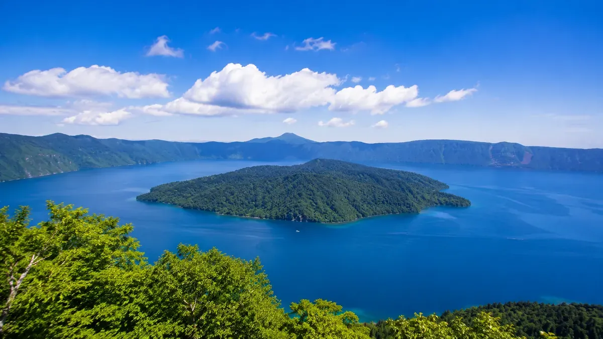 夏の青森県十和田湖畔から眺めるエメラルドグリーンの湖と山々